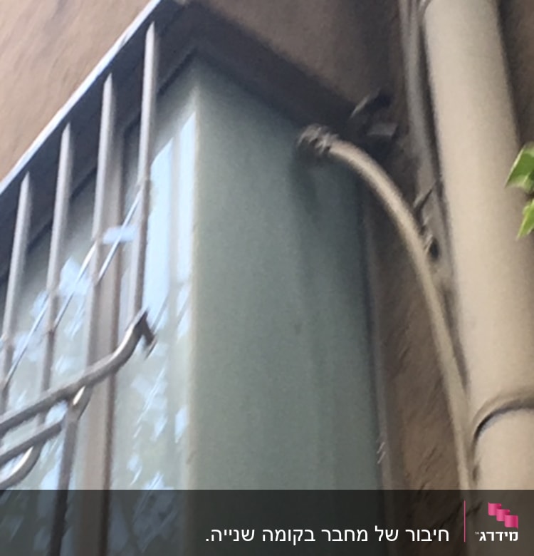 צינור מים מחובר לקיר ליד חלון